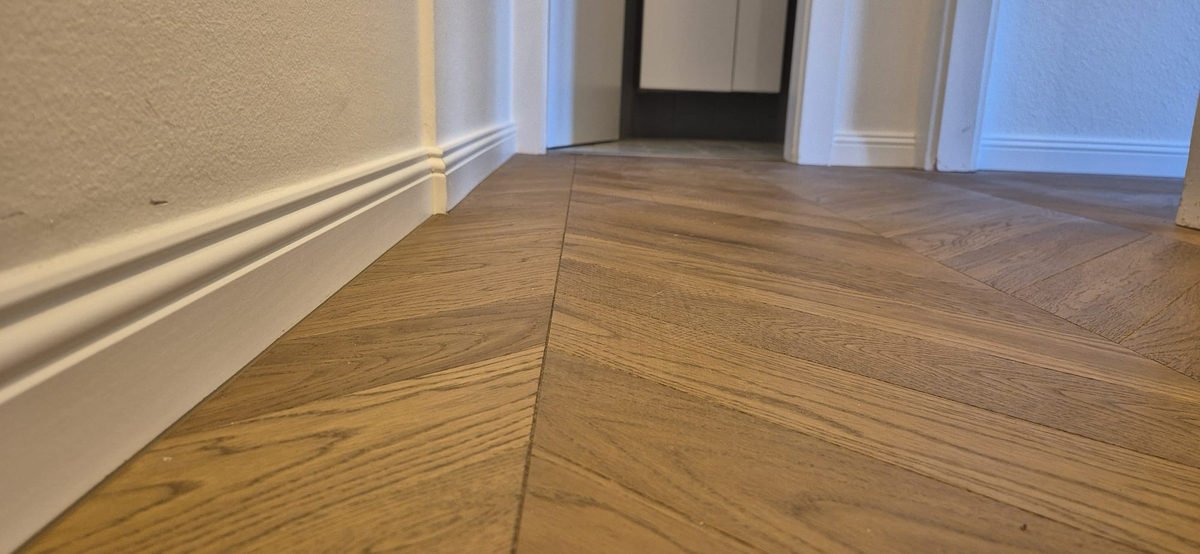 Détail d’un parquet chevron le long d’une plinthe