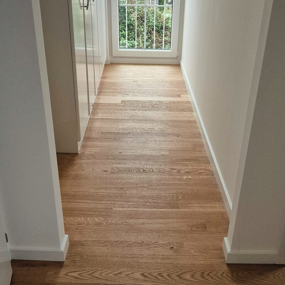 Parquet en lames larges dans un couloir baigné de lumière