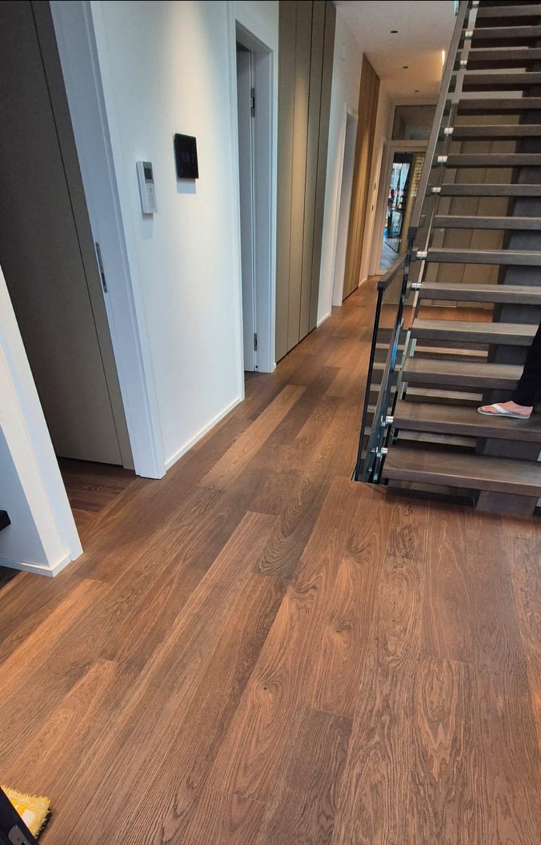 Parquet en lames larges chêne foncé au pied d’un escalier